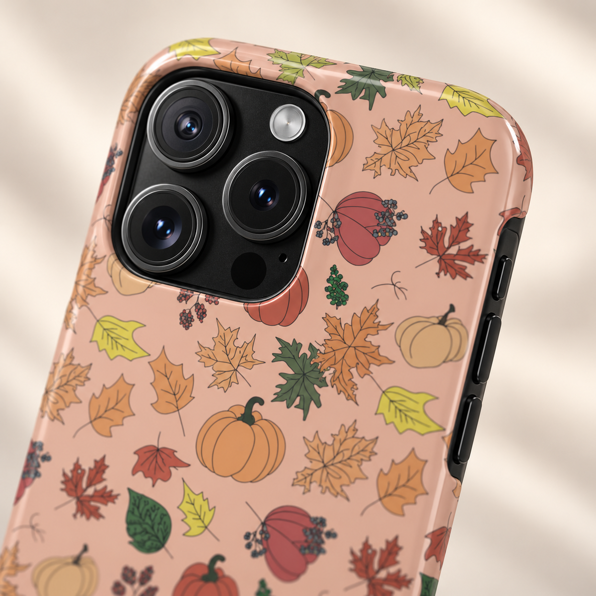 Autumn Harvest MagSafe case, fall leaves, pumpkins and apples on soft peach, lifestyle close-up of the camera