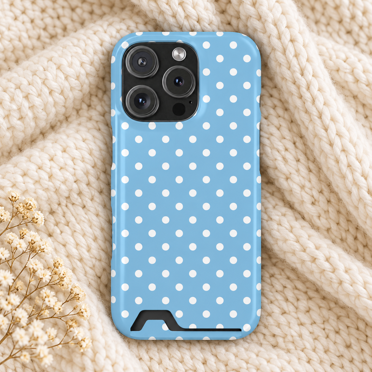 Baby Blue Polka Dot phone case with card holder, white polka dots on baby blue, lifestyle photo on a knit blanket