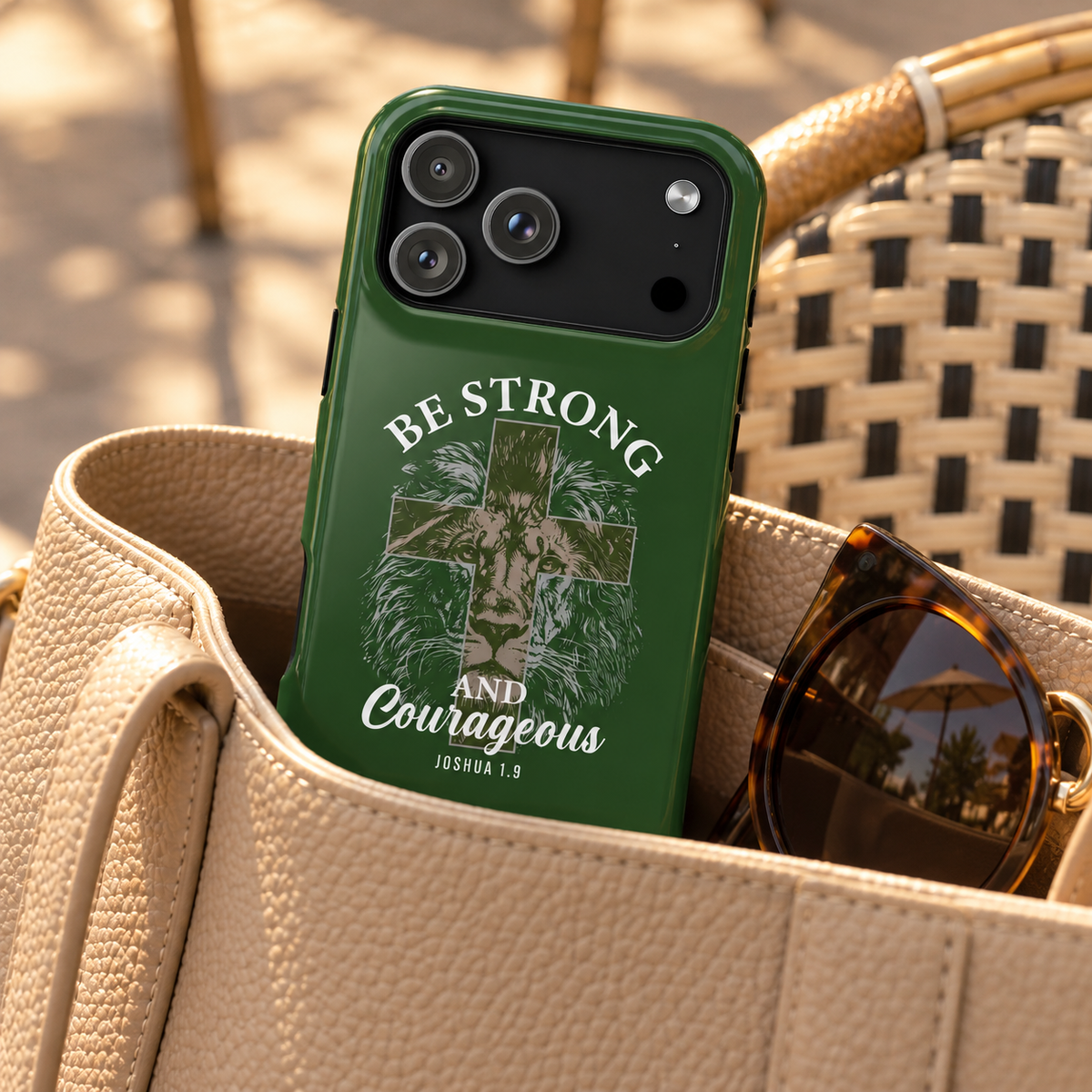 Be Strong Lion phone case with card holder, a lion with Be Strong and Courageous lettering on forest green, lifestyle photo in a handbag