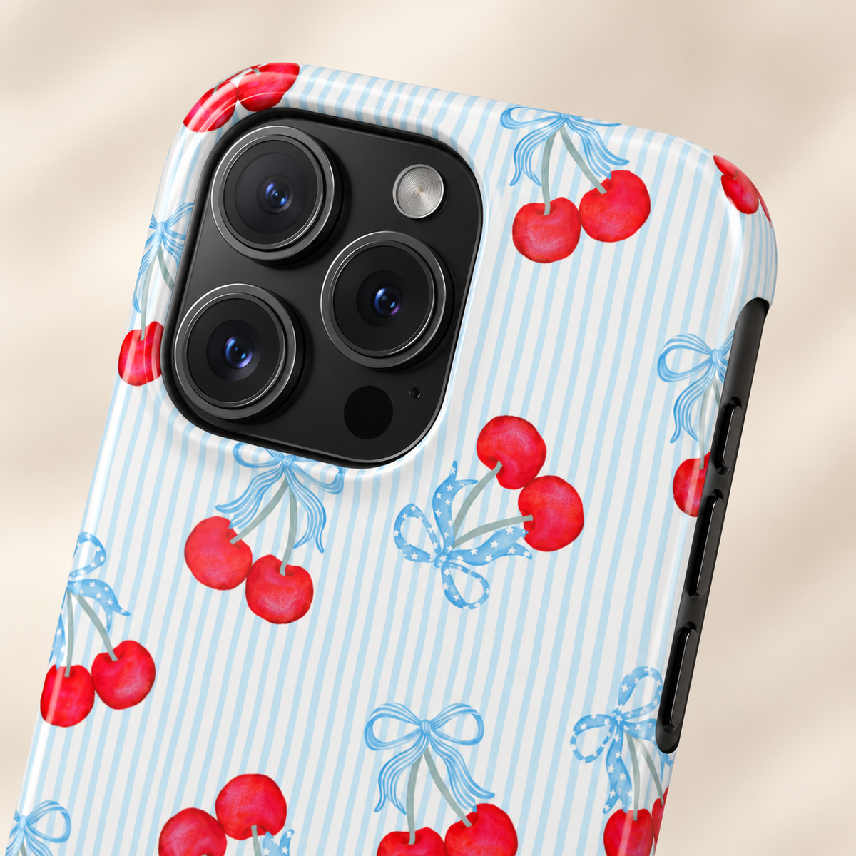 Blue Cherry Bow MagSafe case, red cherries and baby blue bows on blue pinstripes, lifestyle close-up of the camera