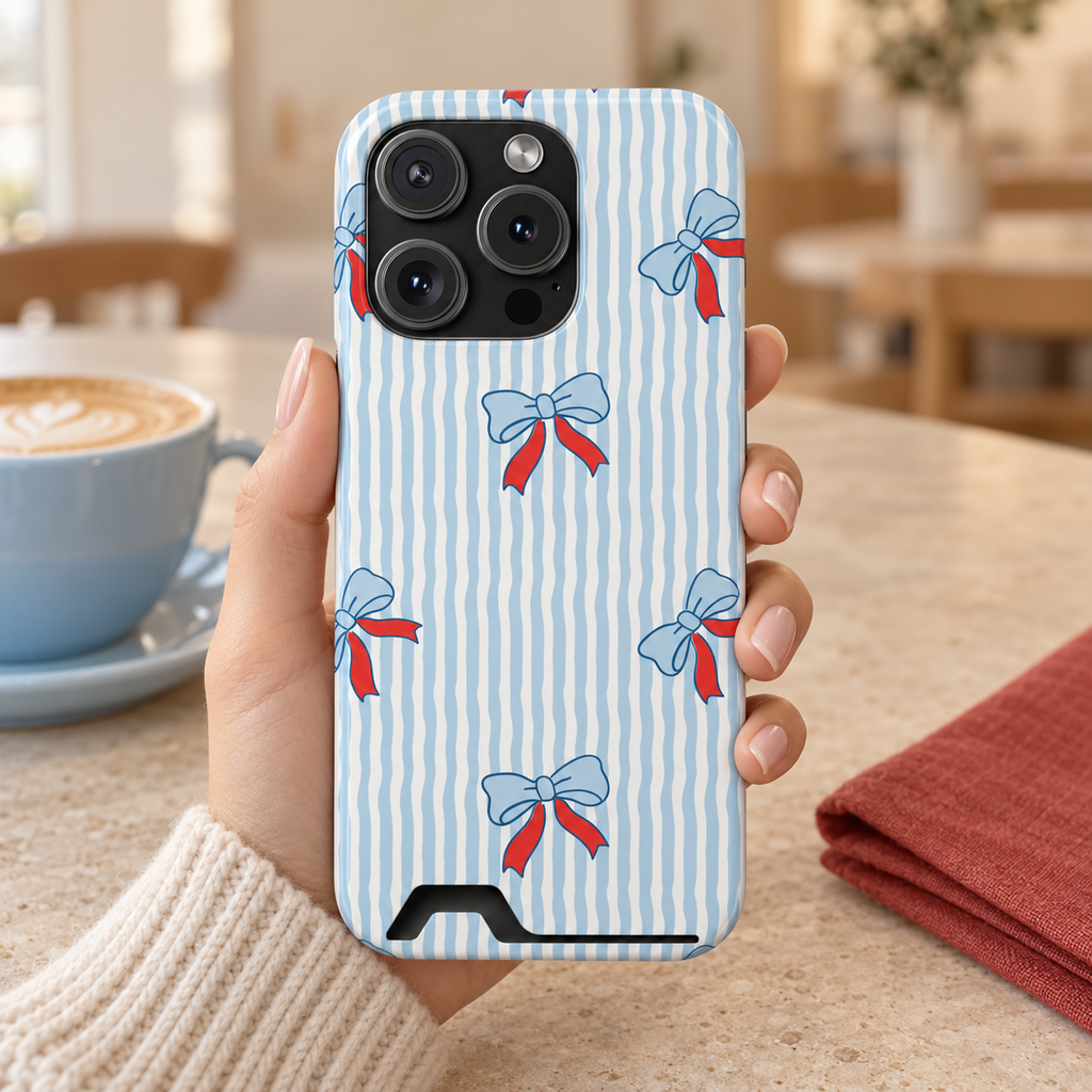 Blue Ribbon Stripe phone case with card holder, baby blue bows with red ribbons on wavy blue stripes, lifestyle photo in hand with coffee