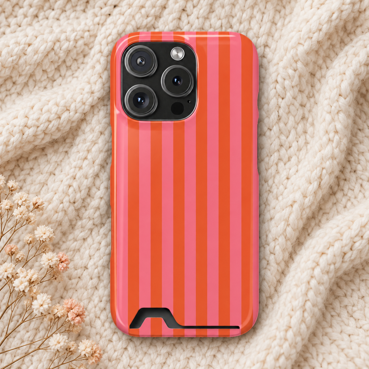 Cabana Stripe phone case with card holder, pink and orange stripes, lifestyle photo on a knit blanket