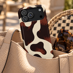 Chocolate Cow phone case with card holder, glossy chocolate brown cow spots on cream, lifestyle photo in a handbag
