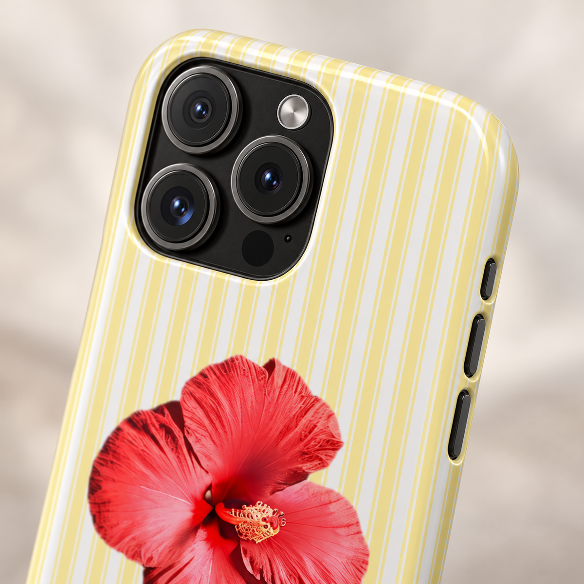 Hibiscus Stripe protective phone case, a red hibiscus on pale yellow stripes, lifestyle close-up of the camera