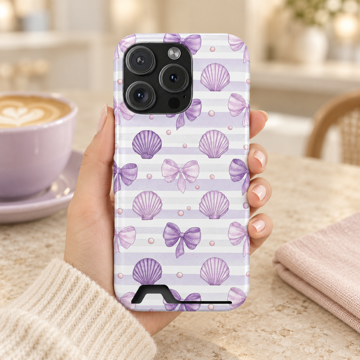 Lilac Seashell phone case with card holder, lilac seashells and bows on soft stripes, lifestyle photo in hand with coffee