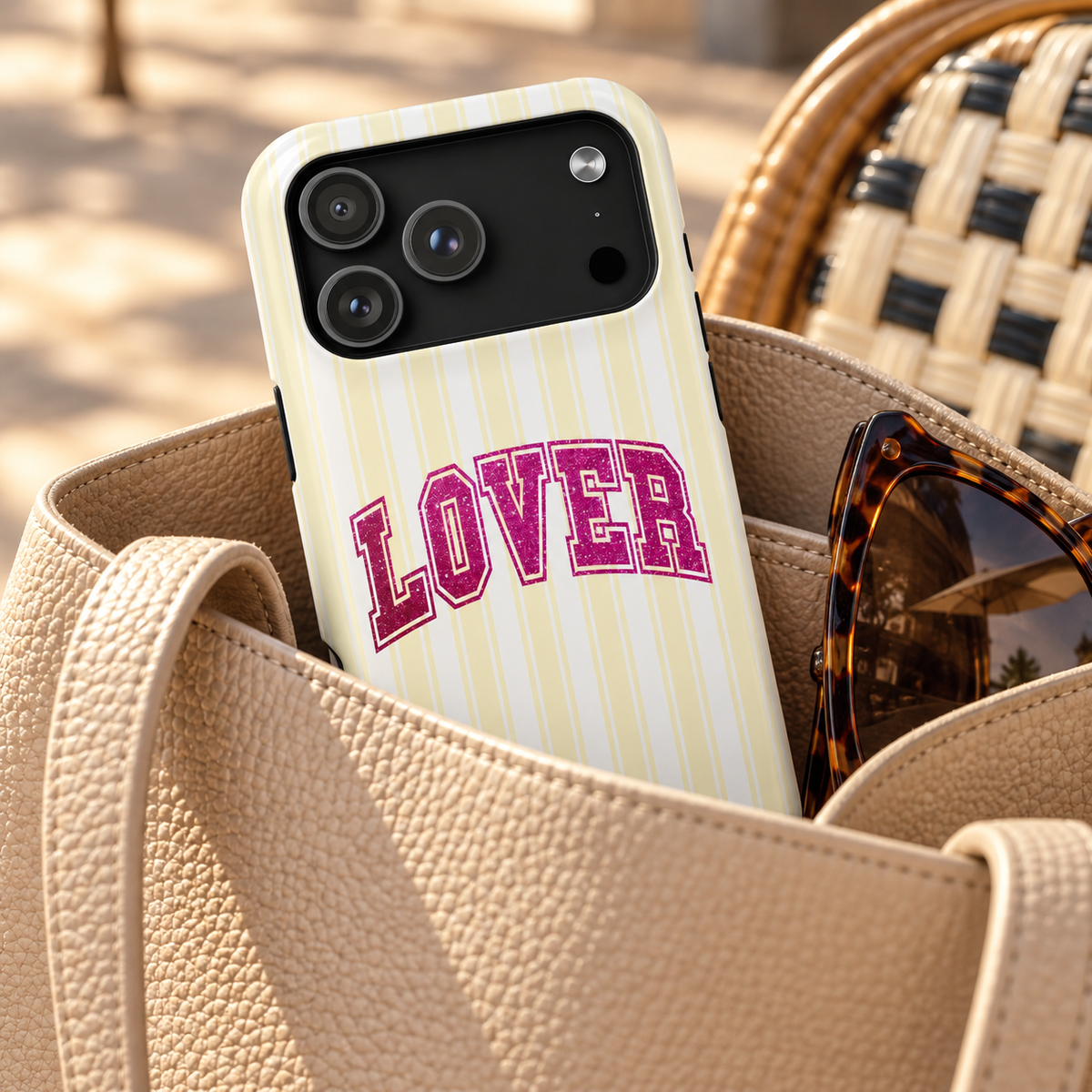 Lover Varsity protective phone case, pink varsity LOVER lettering on pale yellow stripes, lifestyle photo in a handbag