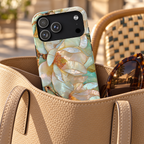 Pearl Magnolia protective phone case, pearly magnolias in soft teal and cream, lifestyle photo in a handbag