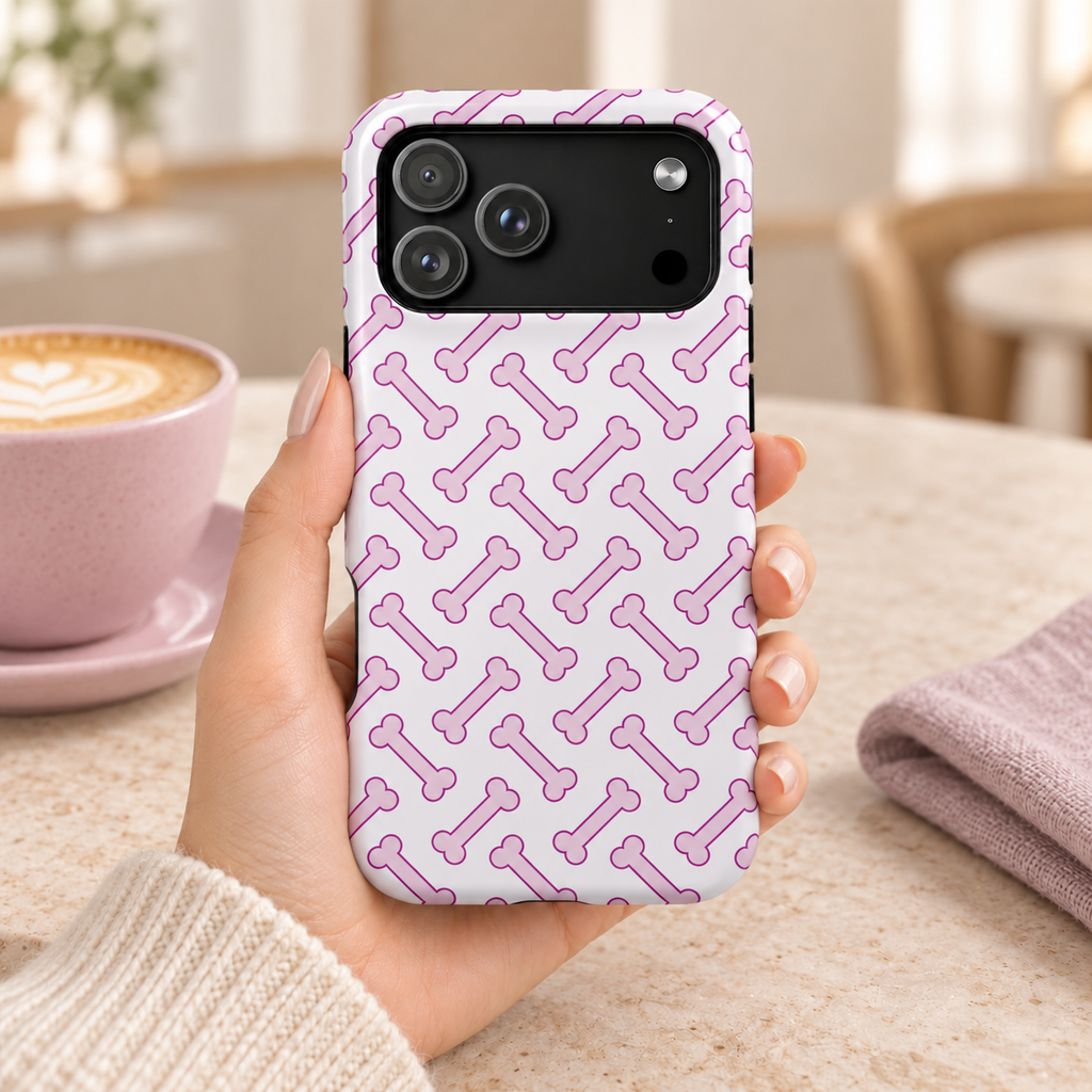 Pink Dog Bone MagSafe case, pink dog bones on white, lifestyle photo in hand with coffee