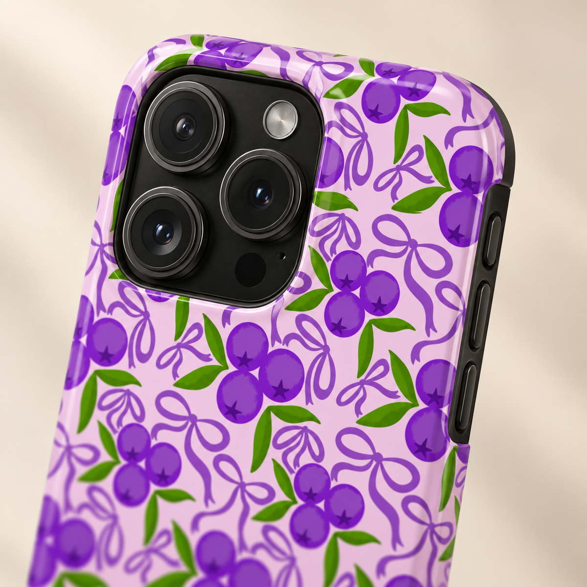 Purple Cherry Bow MagSafe case, purple cherries and ribbons on lilac, lifestyle close-up of the camera