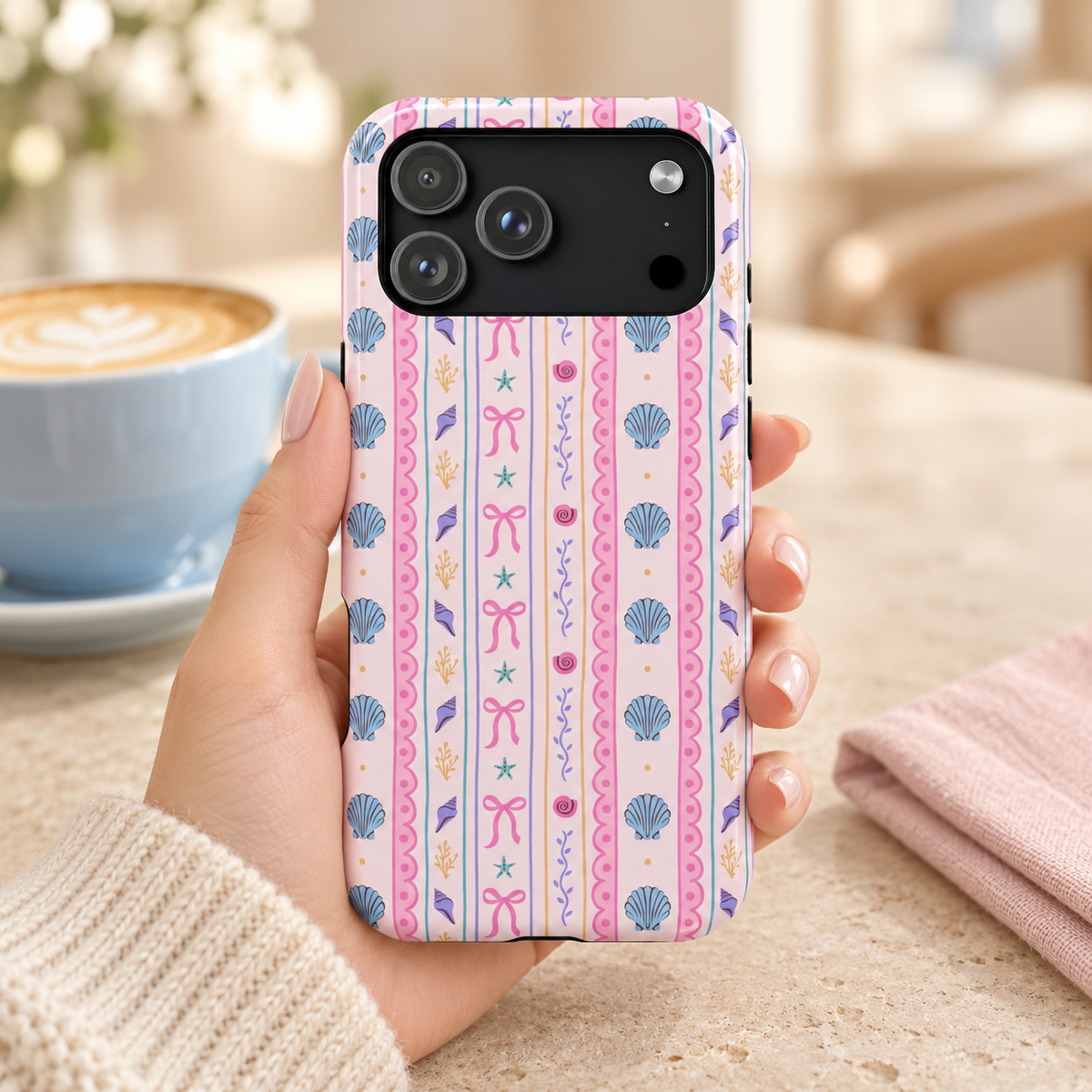 Seashell Ribbon MagSafe case, seashells, starfish and pink bows in pastel stripes, lifestyle photo in hand with coffee