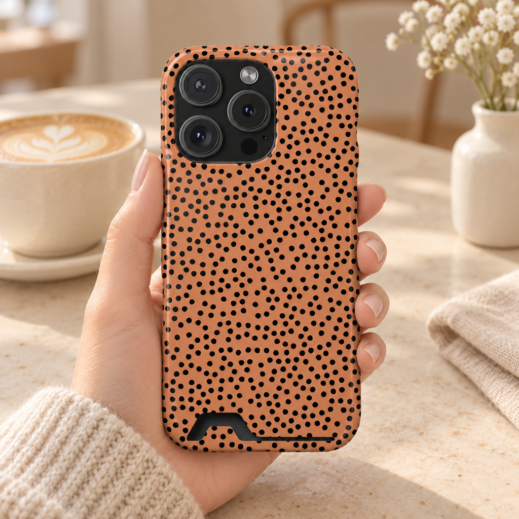 Terracotta Dot phone case with card holder, black spots on warm terracotta, lifestyle photo in hand with coffee